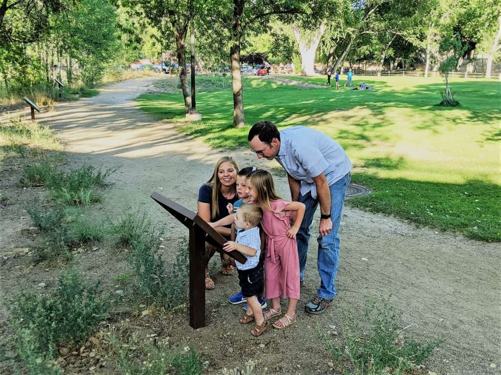 A young family gathers around a storybook panel at Granite Creek Park.